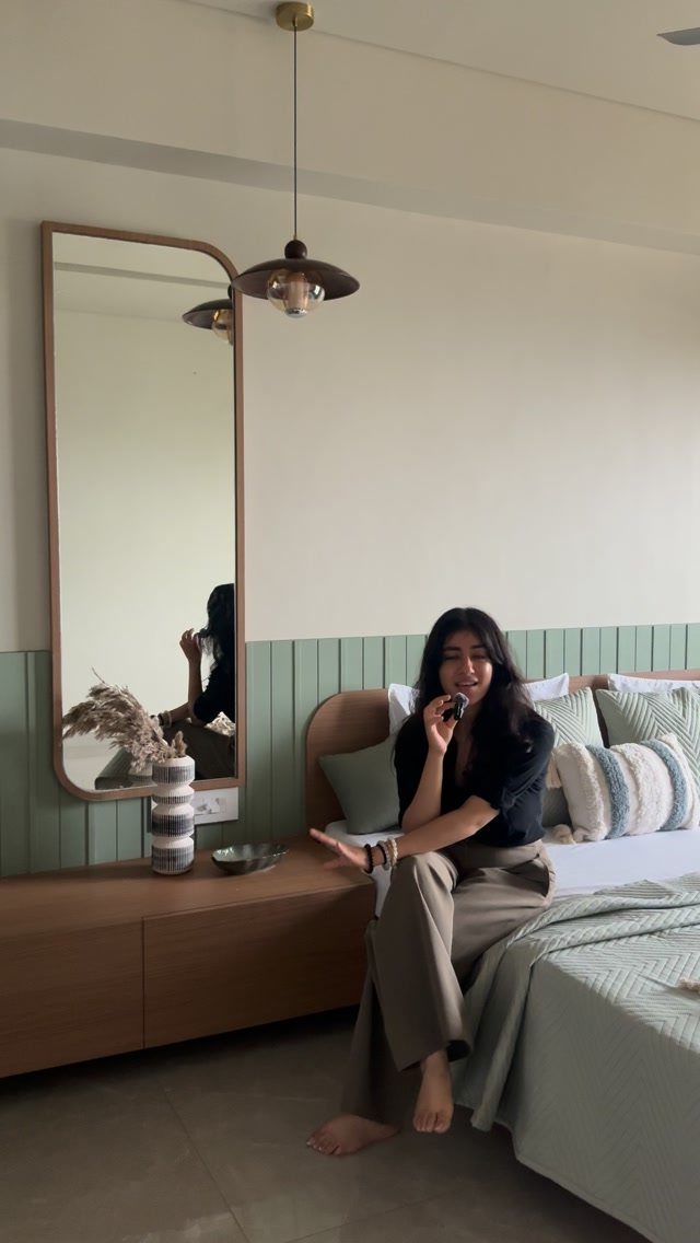 12 Small Bedroom Mirror Ideas That Make a Room Feel Bigger 5 Tall rounded mirror on a green paneled wall in a modern bedroom.