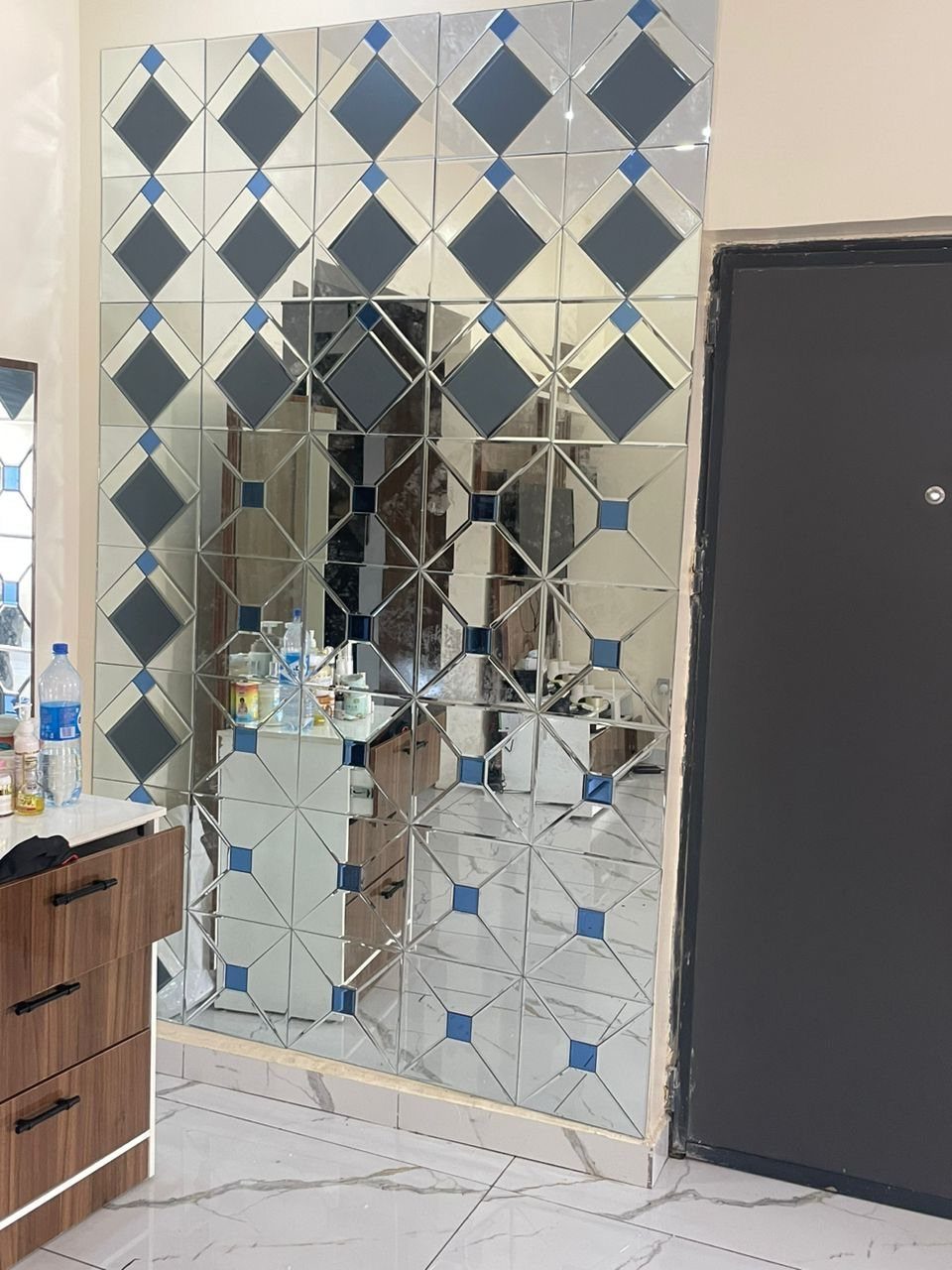 Geometric mirror mosaic wall with blue and clear diamond-shaped mirrored tiles.