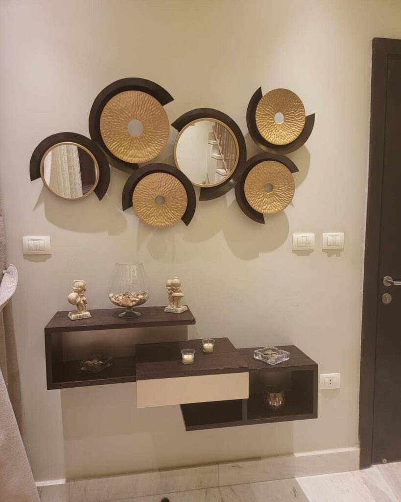 Decorative gold and mirrored circular wall art above a modern dark brown floating shelf.