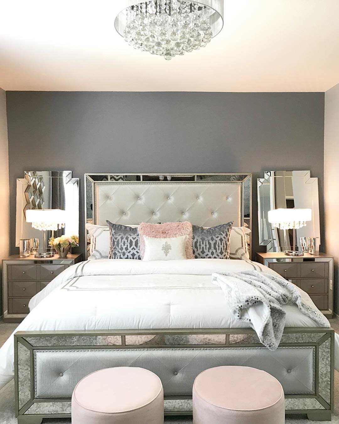 12 Small Bedroom Mirror Ideas That Make a Room Feel Bigger 8 Mirrored bed frame and nightstands in a grey bedroom with pink ottomans.