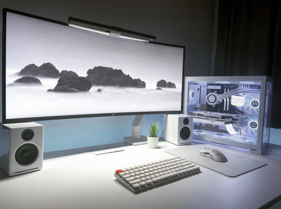 Ultrawide monitor mounted on a white monitor arm in a clean white desk setup