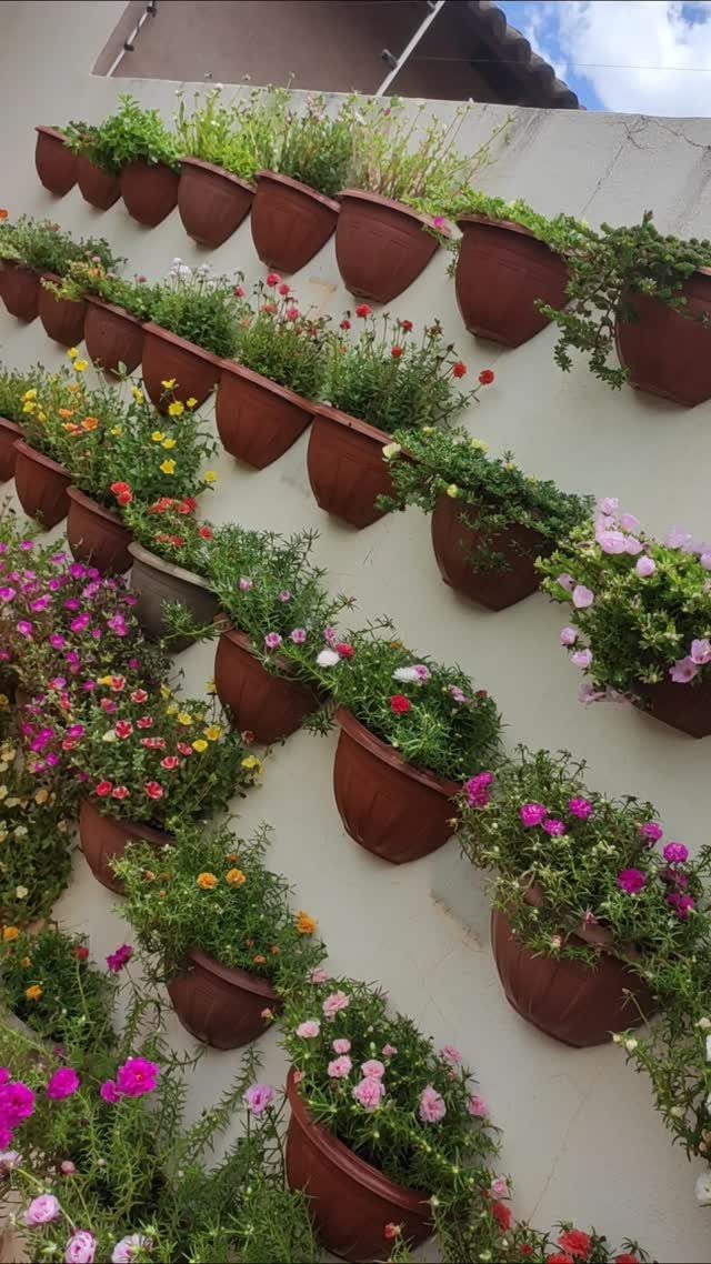 17 Wall Planting Ideas, from Green Walls to Stone Planters 13 Brown plastic pots with colorful flowers mounted in rows on a light wall.