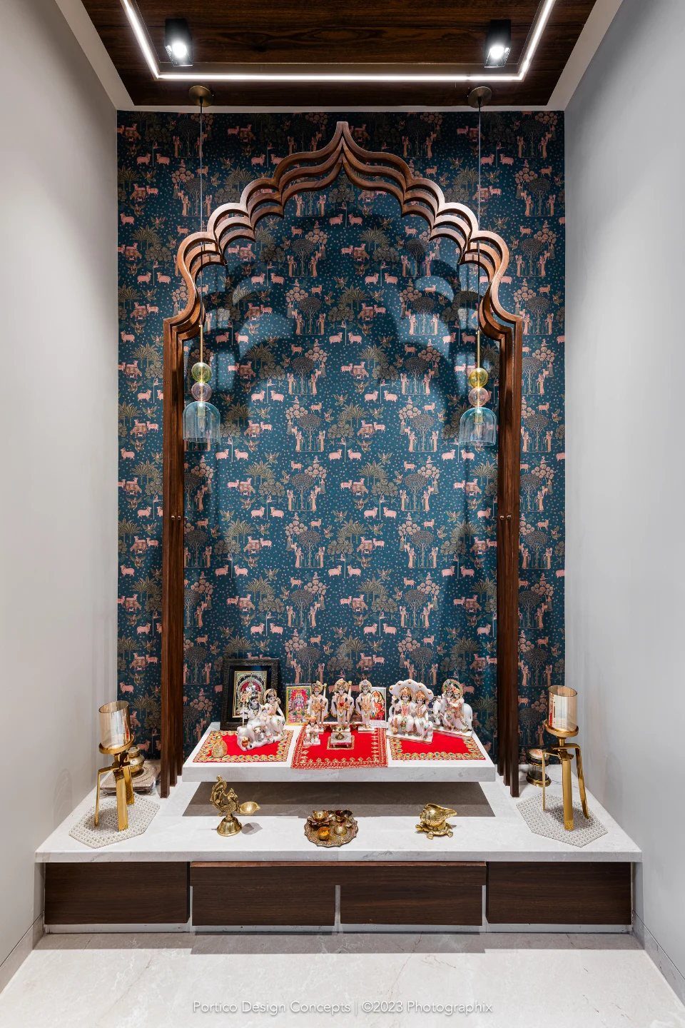 34 Puja Unit Design Modern Ideas for Your Home in 2026 8 Multi-level pooja unit with white marble base, wooden arch, and blue patterned wallpaper.