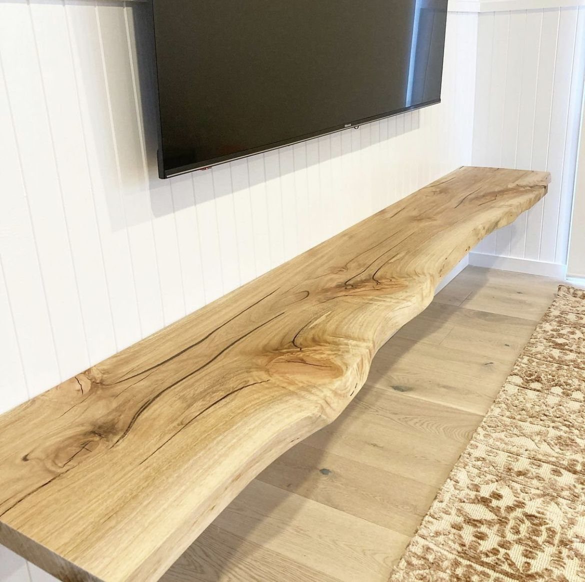 Oak TV Unit Ideas: 17 Styles from Floating to Built-in 15 Live-edge oak floating shelf mounted on a white wall under a television.