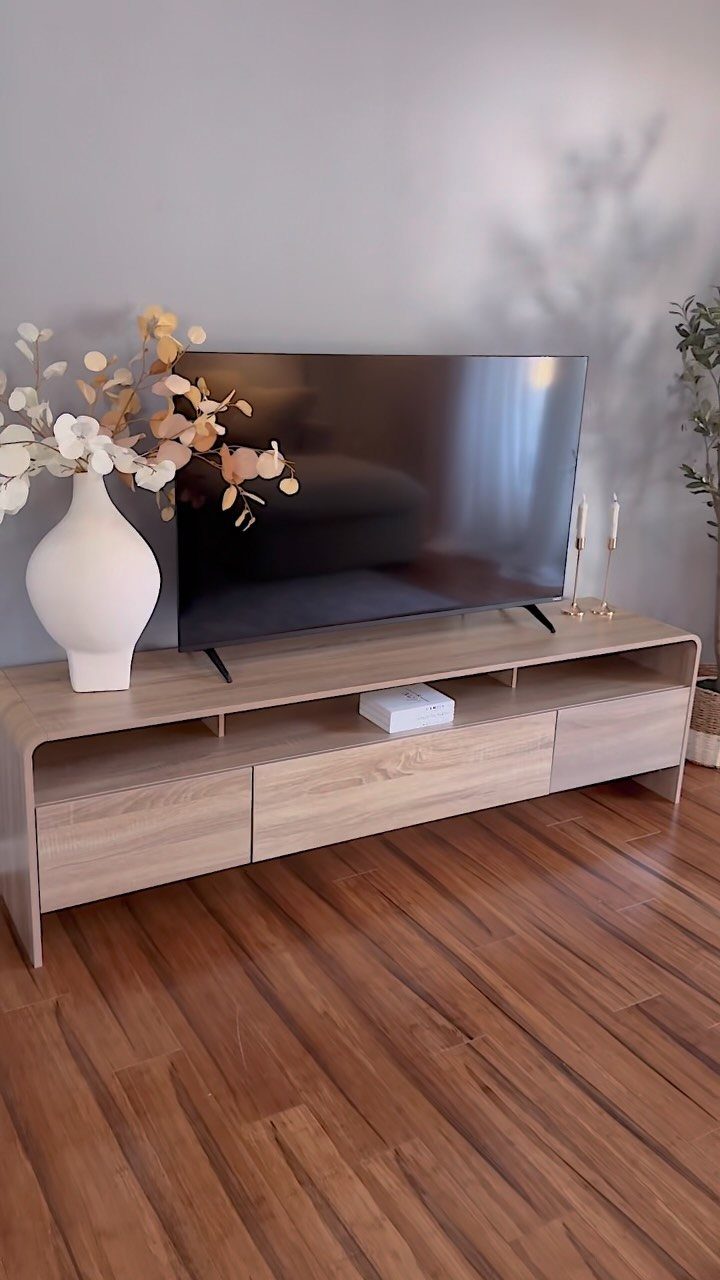 Light wood TV unit with an open shelf and drawers on wooden flooring