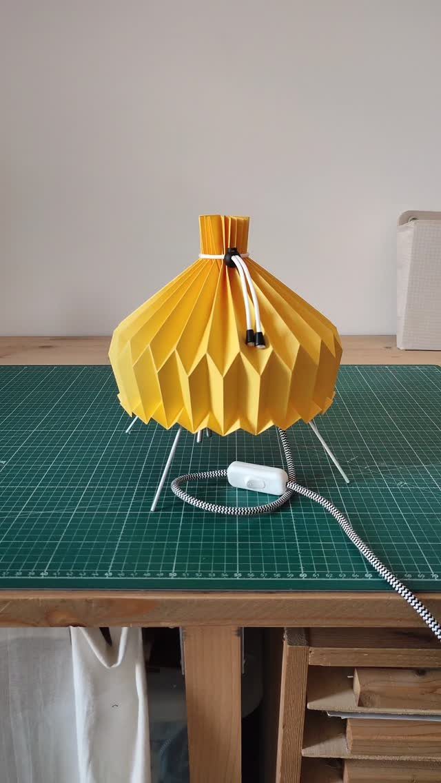 Make Table Lamp Ideas: 14 Designs in Wood, Glass and Ceramic 14 Yellow pleated paper table lamp with white cord on a green cutting mat.