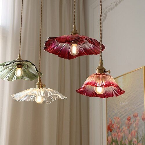 40 Home Decor Item Ideas, From Candle Holders to Sculptures 11 Four flower-shaped glass pendant lights in various colors hanging against a white curtain.
