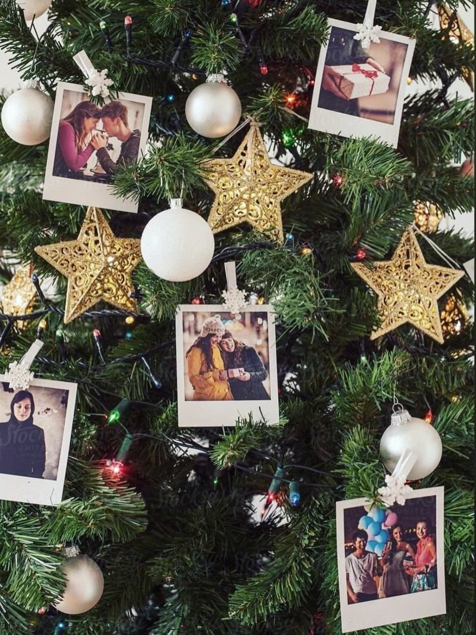 Christmas tree decorated with gold stars, white ornaments, and Polaroid photos clipped to branches.