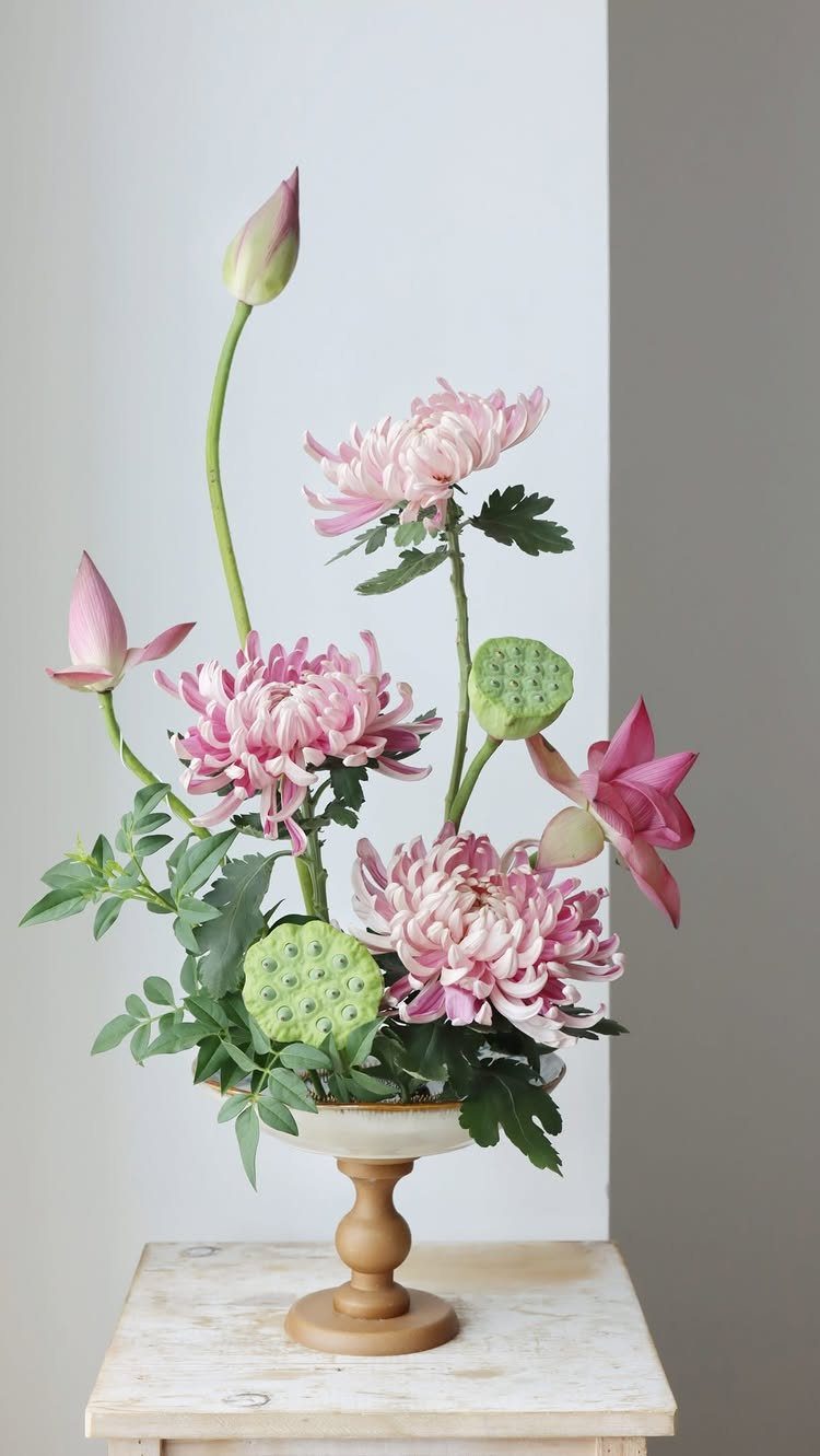 34 Large Floral Arrangement Ideas for Tables, Trays and Vases 31 Pink chrysanthemums and lotus buds in a pedestal bowl on a white table.