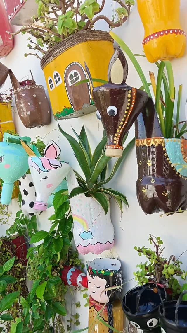 17 Wall Planting Ideas, from Green Walls to Stone Planters 9 Painted plastic bottle planters shaped like animals and houses on a white wall.