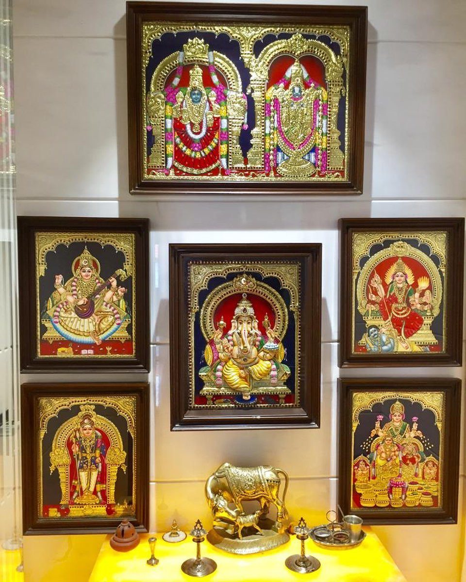 34 Puja Unit Design Modern Ideas for Your Home in 2026 31 Framed deity paintings on a white wall above a yellow altar with brass lamps.