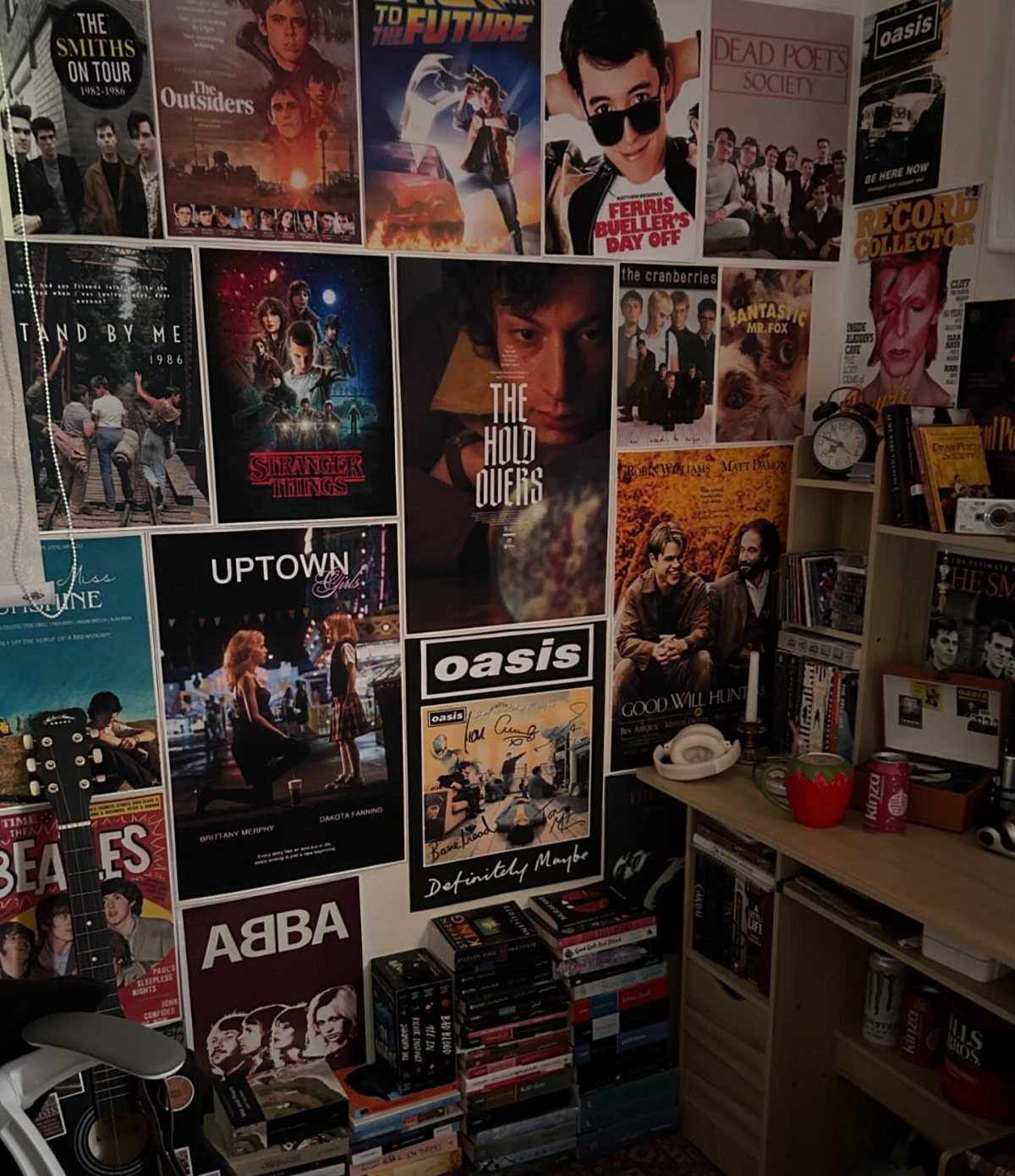 13 Alt Room Decor Ideas with Moody Colors, Wood, and Plants 3 Wall covered in eclectic movie and music posters with a guitar and bookshelf.