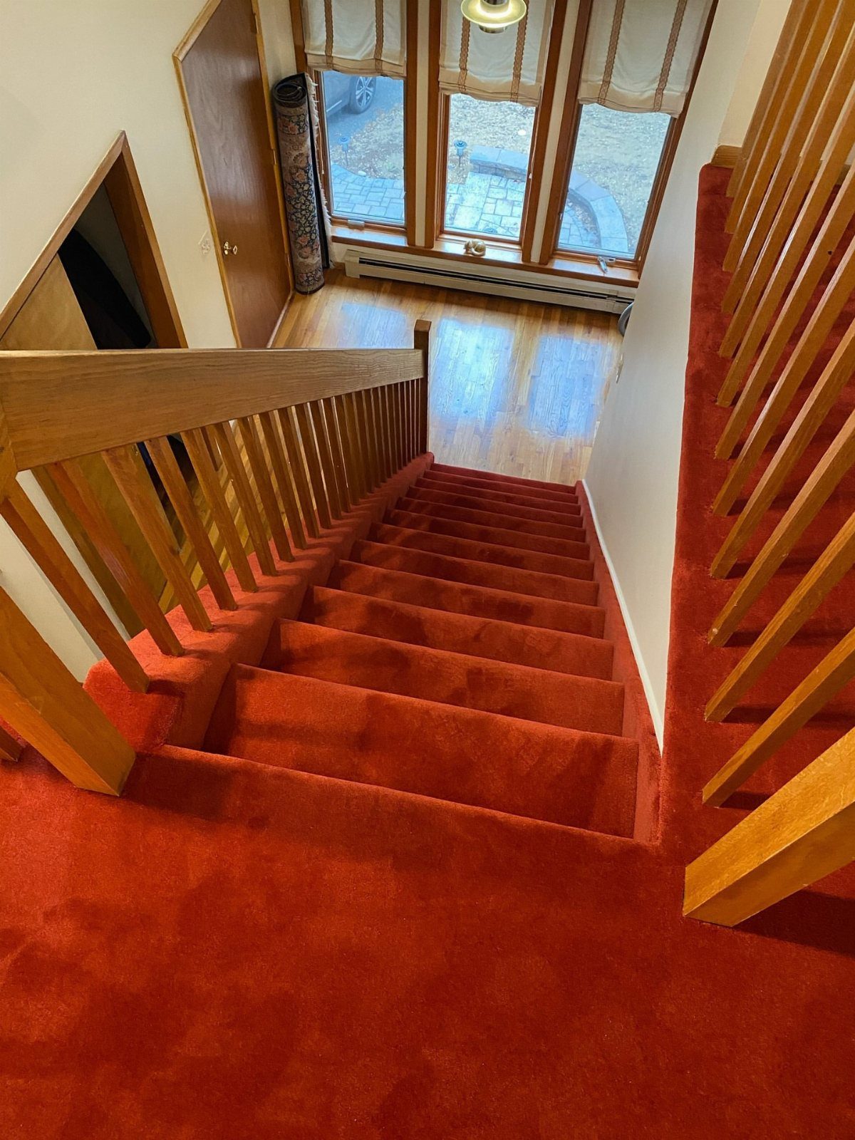 Stairs with Carpet: 23 Styles from Runners to Bold Patterns 12 Red carpeted stairs with wooden railings leading down to a light wood floor.