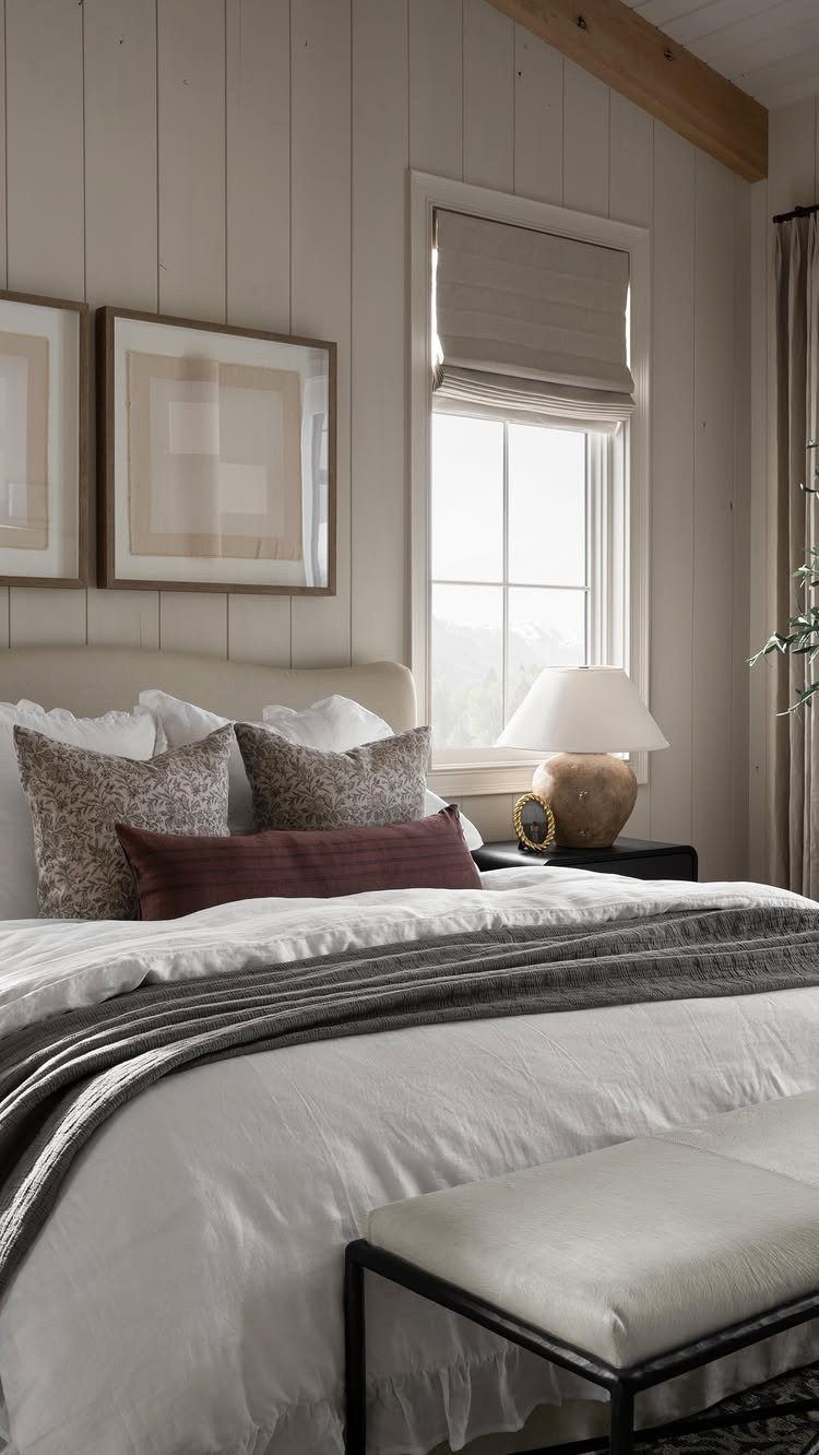 Neutral Roman shade on a window in a bright, white paneled bedroom