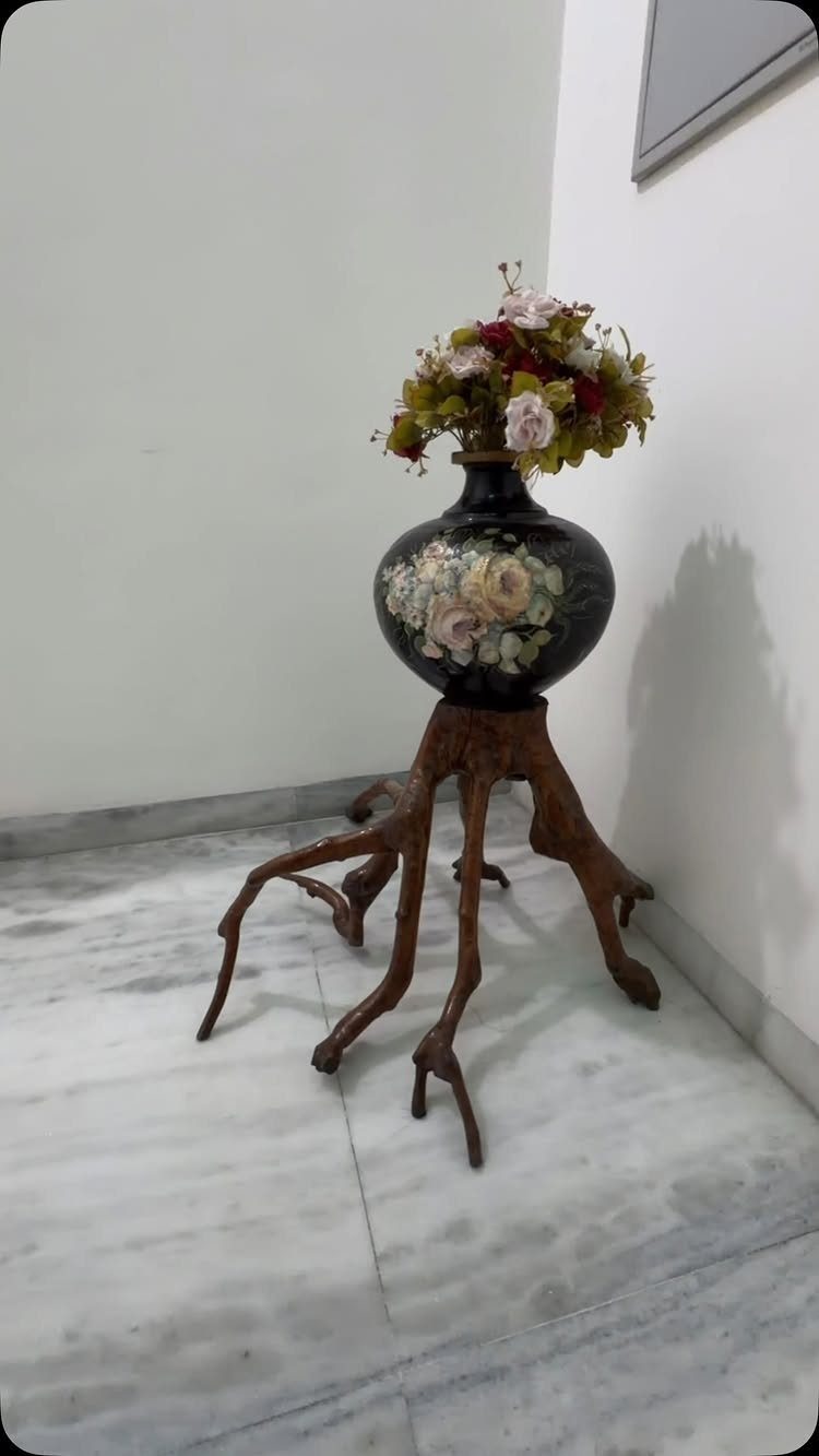 38 Flower Pot on Stand Ideas, from Iron Frames to Pedestals 33 Root-shaped wooden stand holding a black floral vase with a flower bouquet.