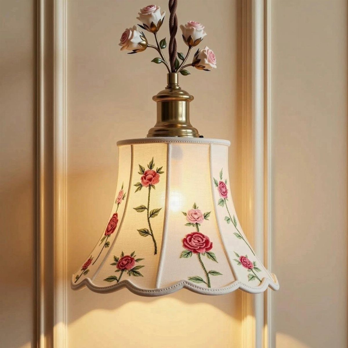 Cream bell-shaped lamp shade with pink rose patterns and floral brass topper.