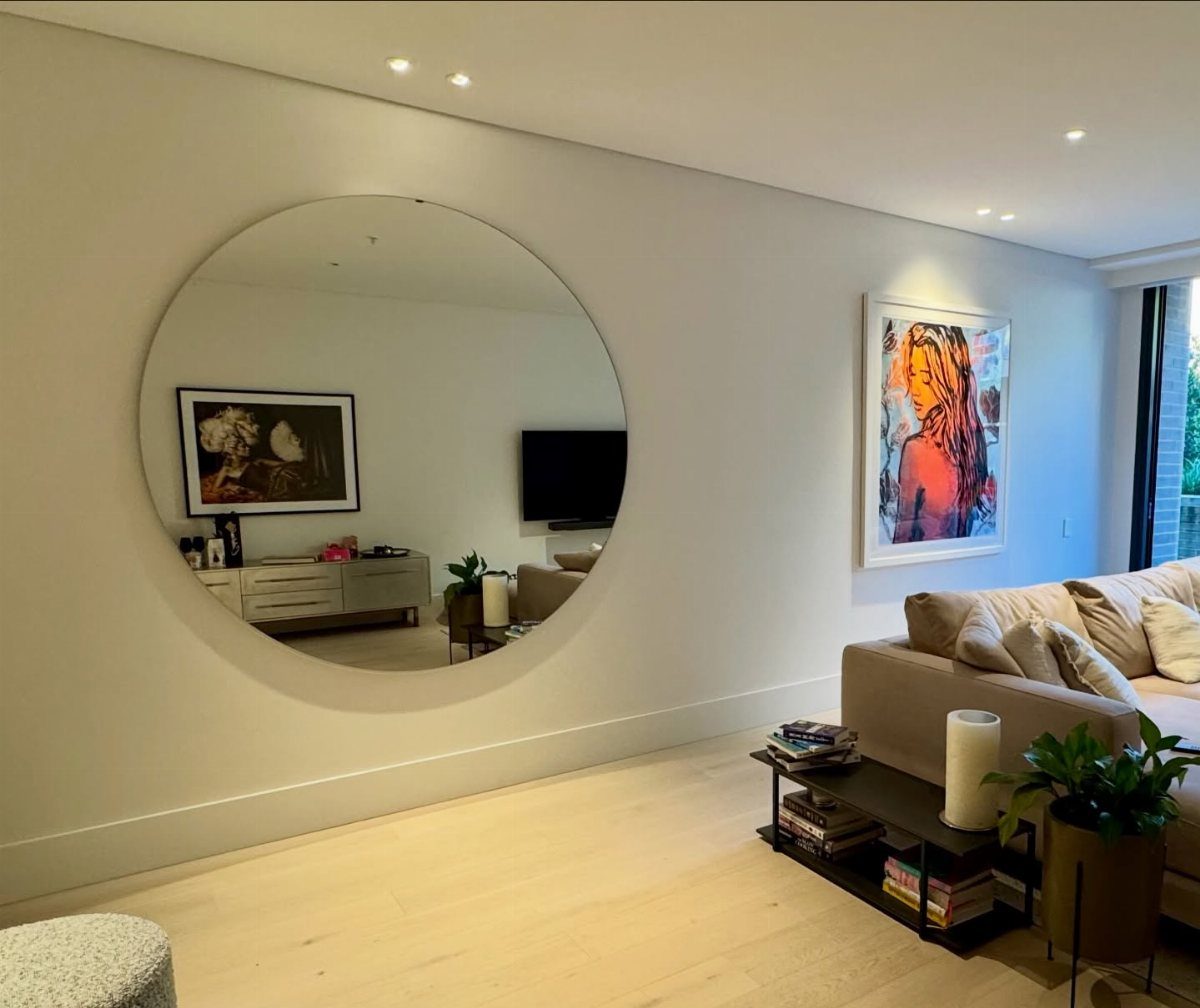 Large round frameless mirror on a white wall in a modern living room