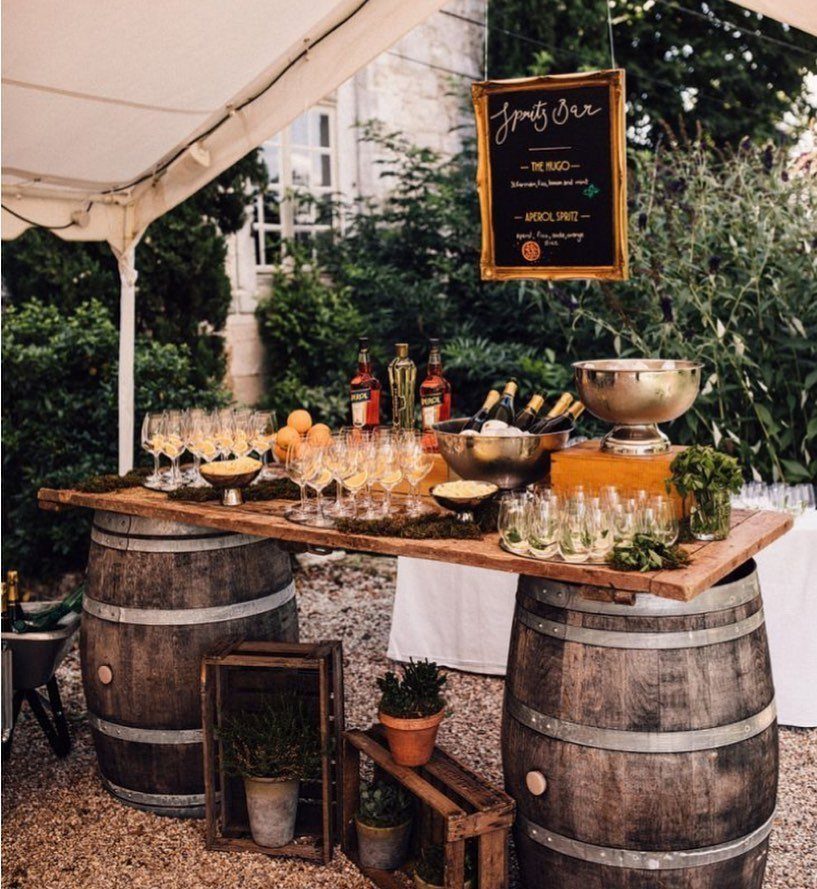 Rustic outdoor bar with a wooden slab top supported by two large wine barrels.