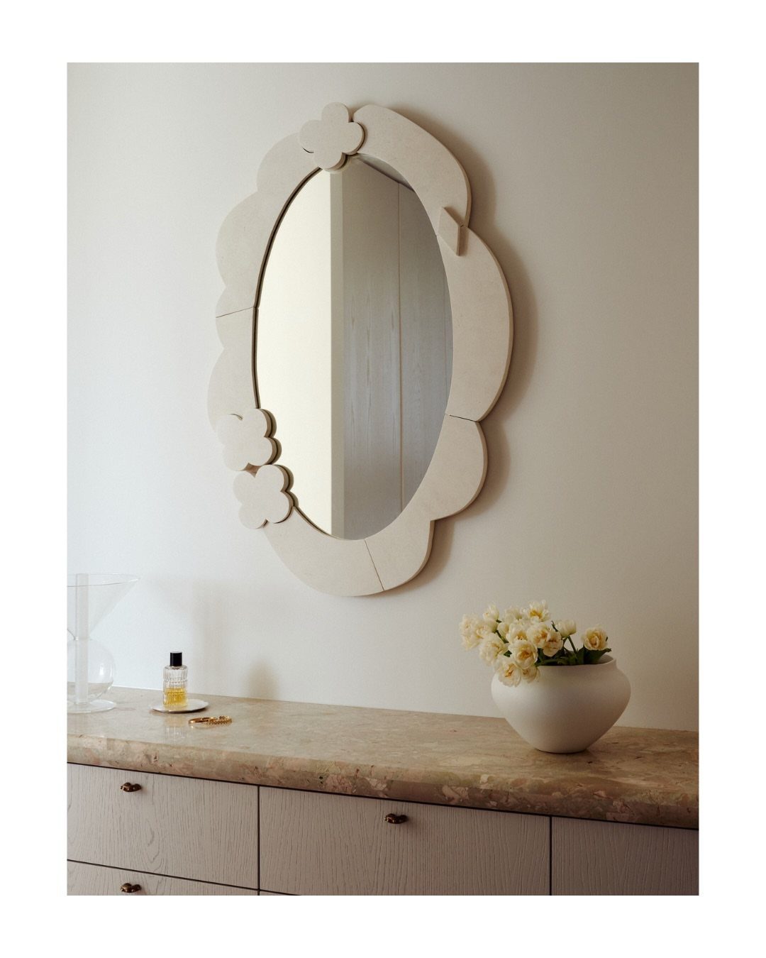 Mirror Wall Art: 25 Ideas from Sunburst to Floor Mirrors 9 Oval mirror with a cream scalloped frame hanging above a stone countertop.