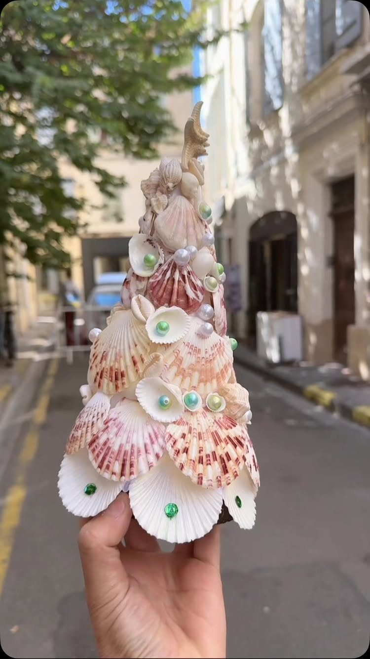 Seashell Christmas tree decorated with pearls and beads held in a person's hand.