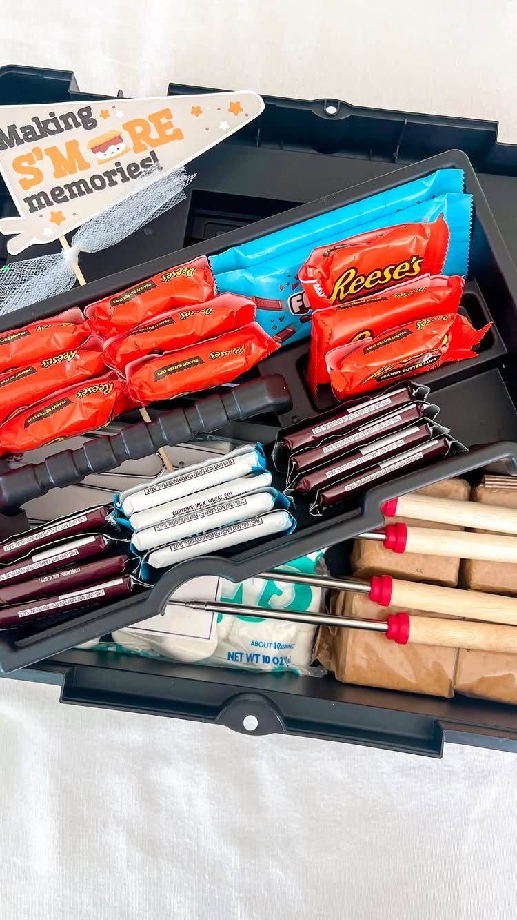 S'mores gift basket in a black tray with candy, chocolate, and roasting sticks.