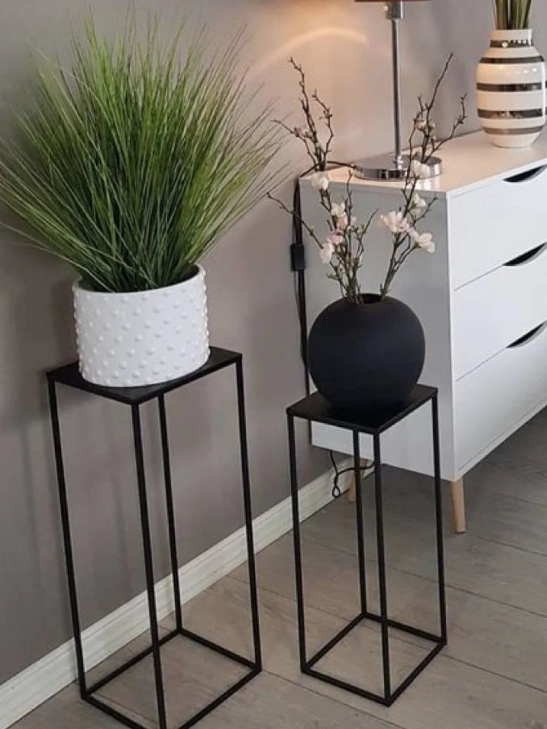 38 Flower Pot on Stand Ideas, from Iron Frames to Pedestals 11 Two black metal square-base plant stands holding a white pot and black vase.