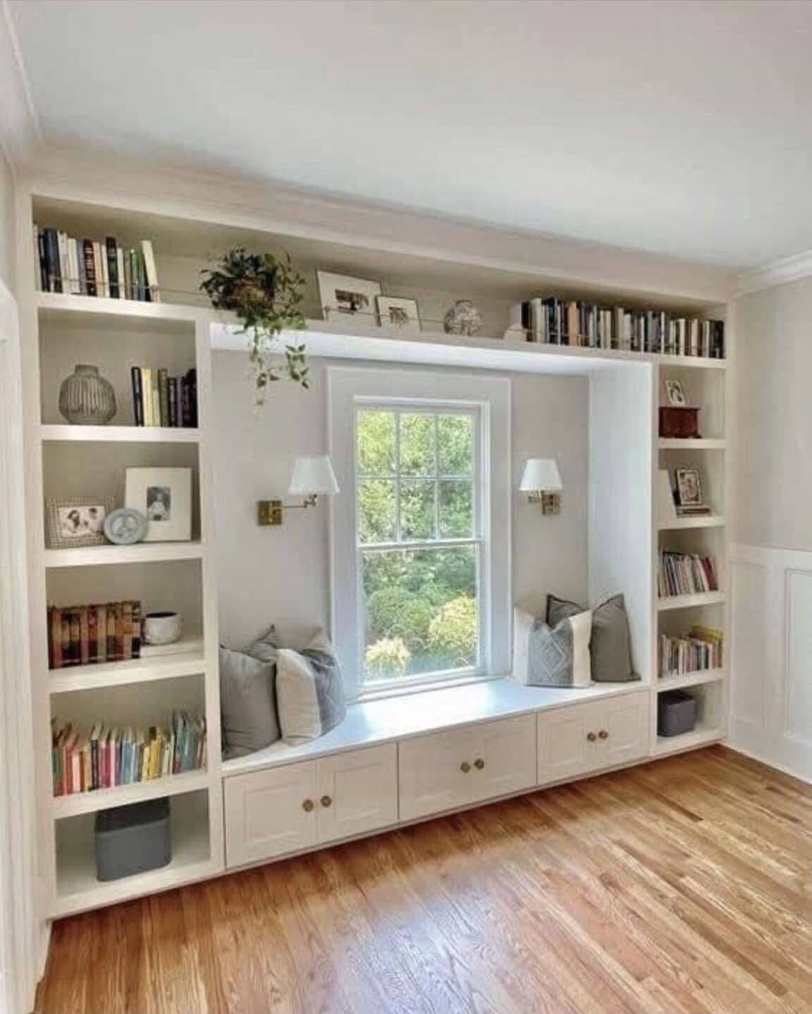 White built-in window seat with storage drawers underneath and flanking bookshelves.