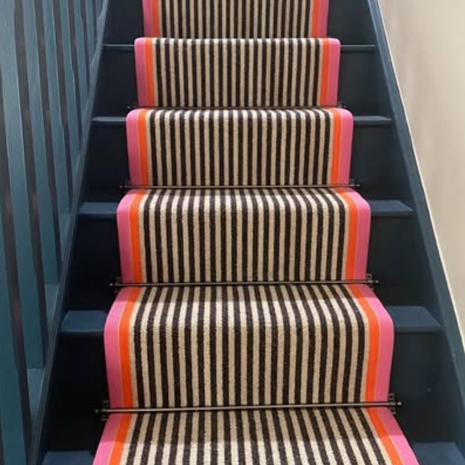 Stairs with Carpet: 23 Styles from Runners to Bold Patterns 1 Striped carpet runner with pink and orange borders on dark blue stairs.
