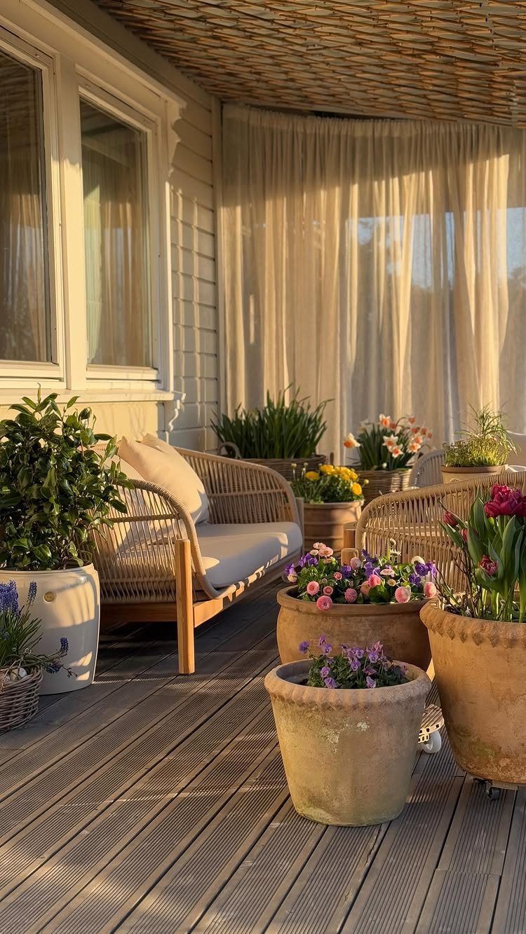 House Plant Pots: 21 Ideas in Ceramic, Terracotta and Metal 2 Terracotta plant pots with colorful flowers on a wooden deck beside a wicker sofa.
