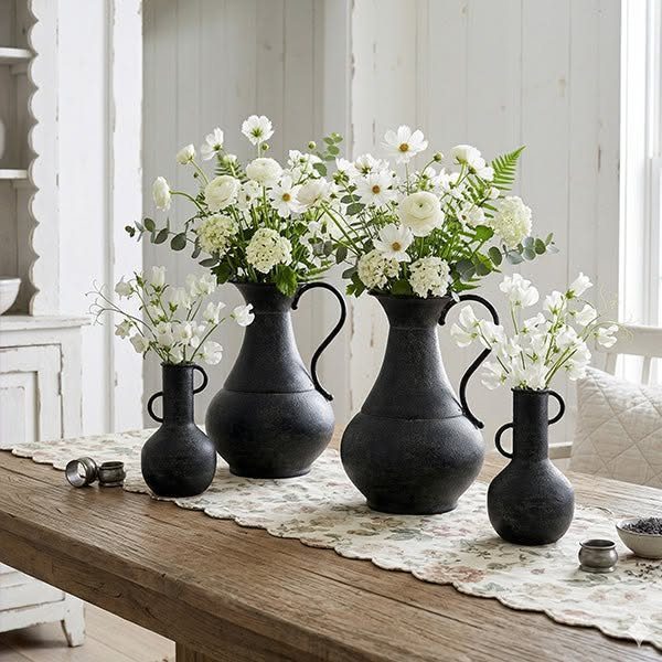 40 Home Decor Item Ideas, From Candle Holders to Sculptures 29 Black textured iron ewer vases with white flowers on a rustic wooden table.