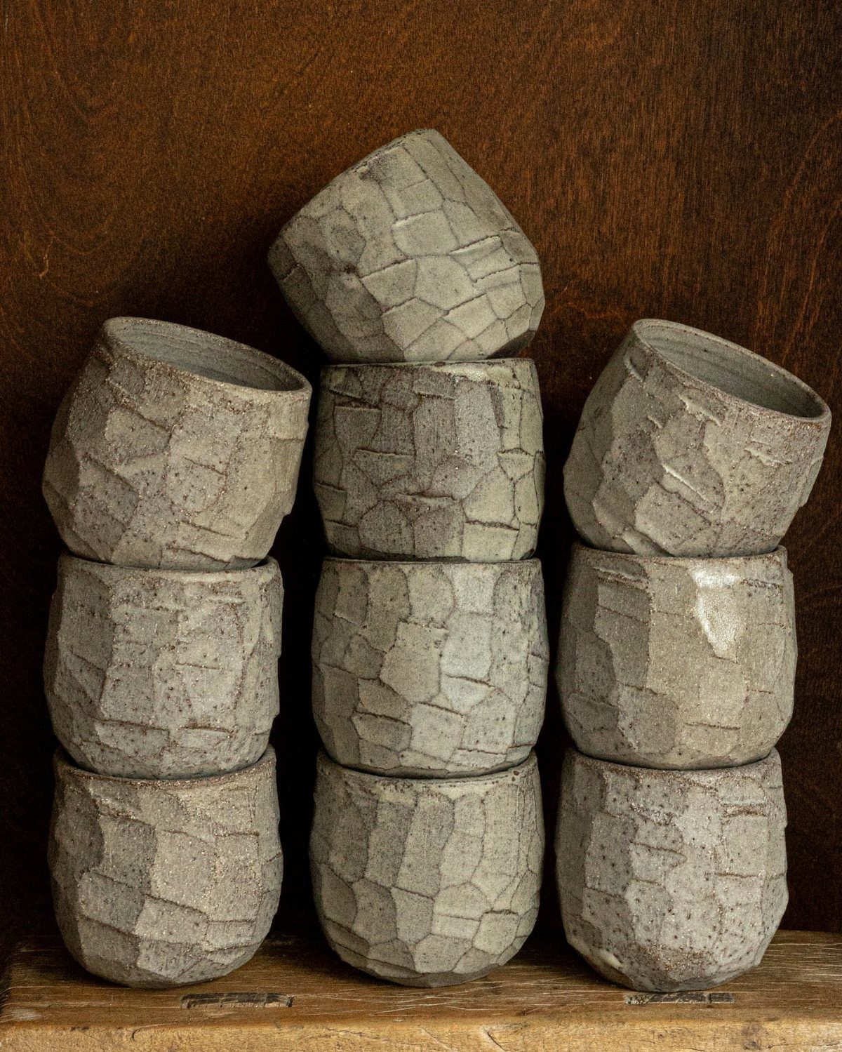 30 DIY Clay Crafts to Make with Air-Dry Clay for Home Decor 22 Grey clay vessels with textured slab surfaces stacked in three columns on wood.