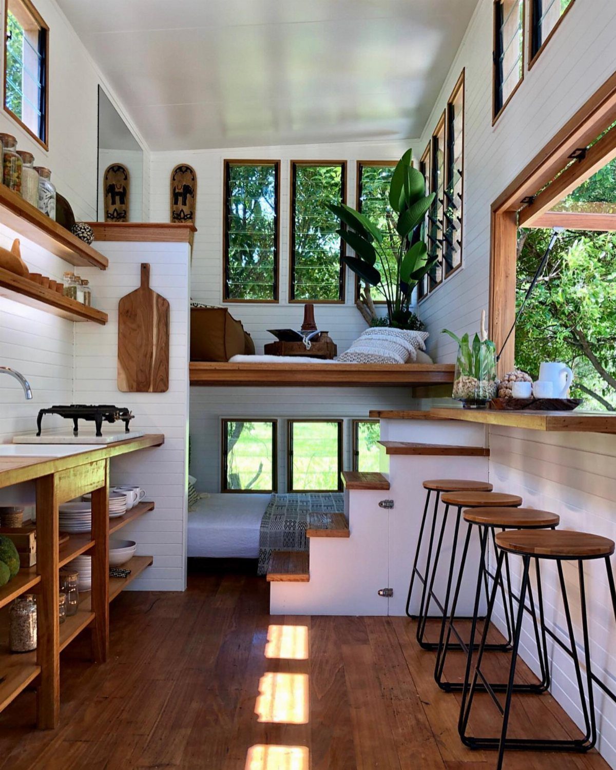 Tiny house interior with open kitchen, dining bar, and multi-level sleeping areas.