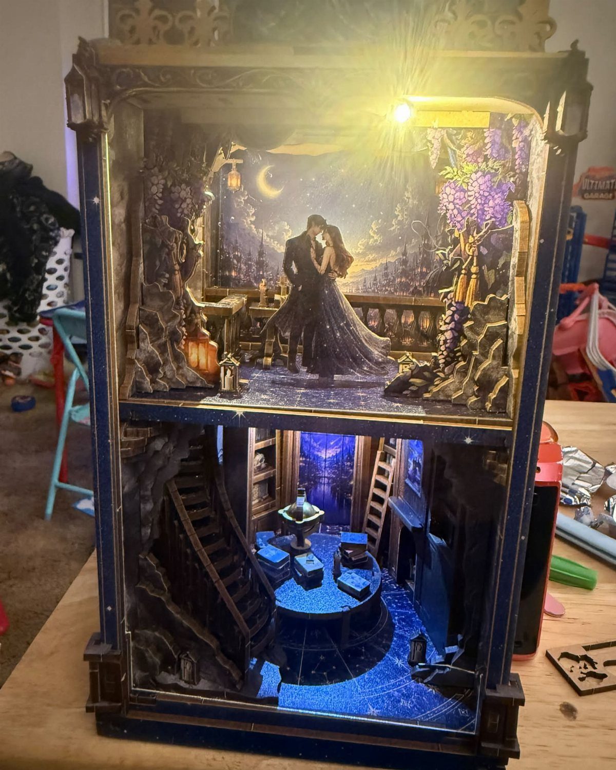 Two-story miniature book nook diorama with a romantic scene and a blue-lit room.
