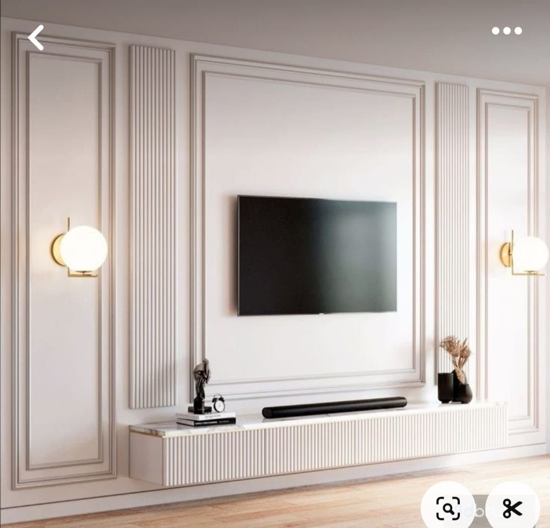 Wall-mounted TV surrounded by white rectangular molding panels and a fluted floating console.