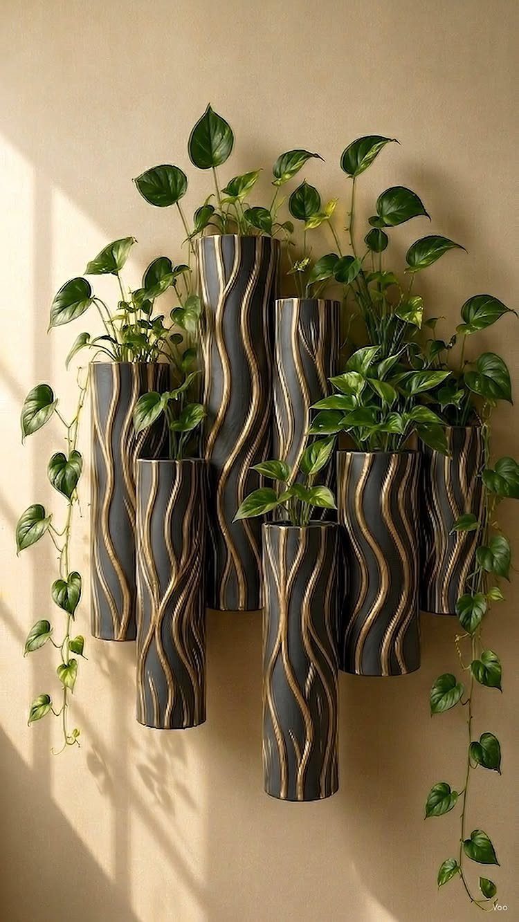 40 Home Decor Item Ideas, From Candle Holders to Sculptures 37 Dark grey cylindrical wall planters with gold accents holding green trailing foliage.