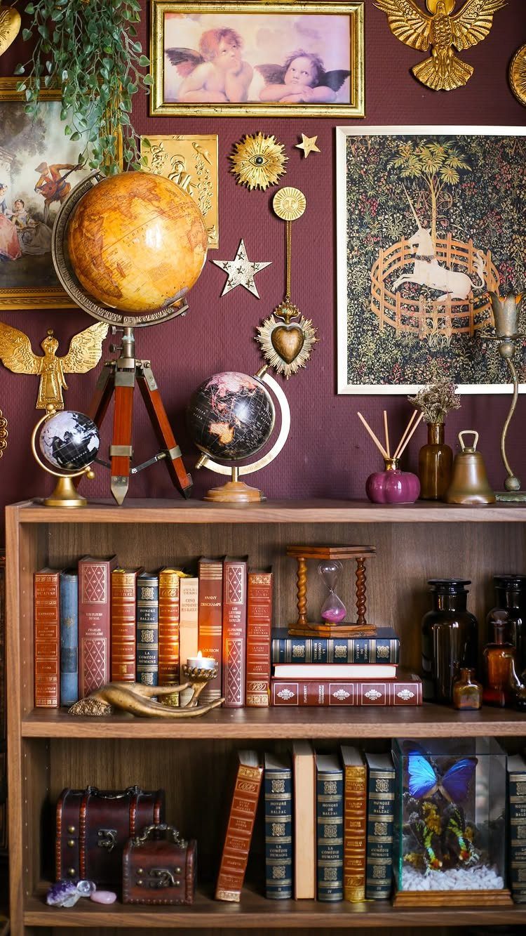 Wooden bookshelf with old books and globes against a purple wall with gold ornaments.