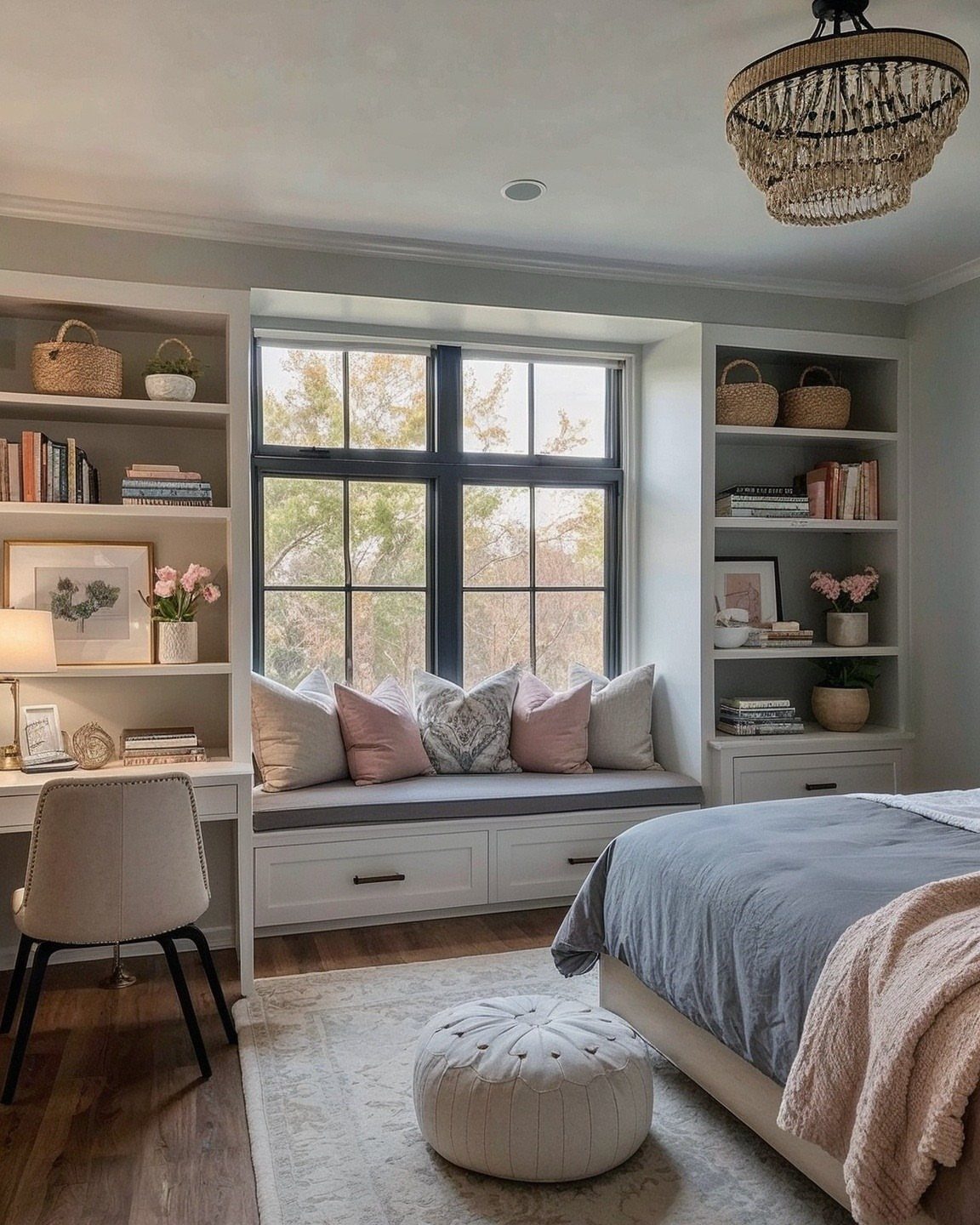 Window reading nook with a cushioned bench, pink pillows, and flanking white bookshelves.