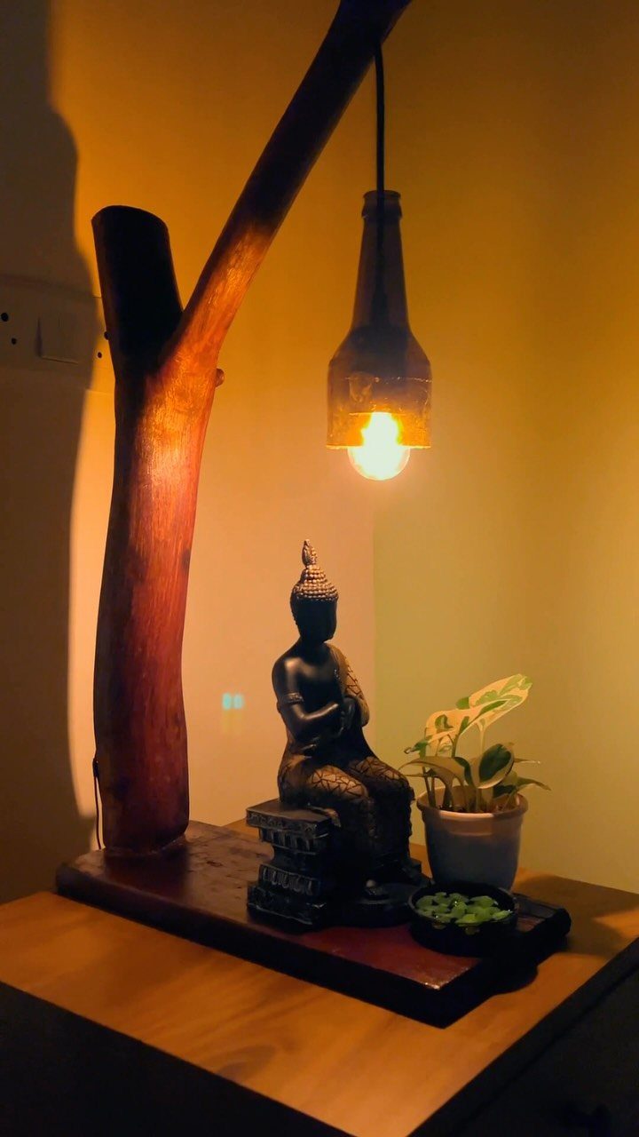 17 Handmade Lamps Ideas Using Wood, Concrete, and Glass Jars 6 Industrial bottle lamp hanging from a curved wooden branch above a Buddha statue