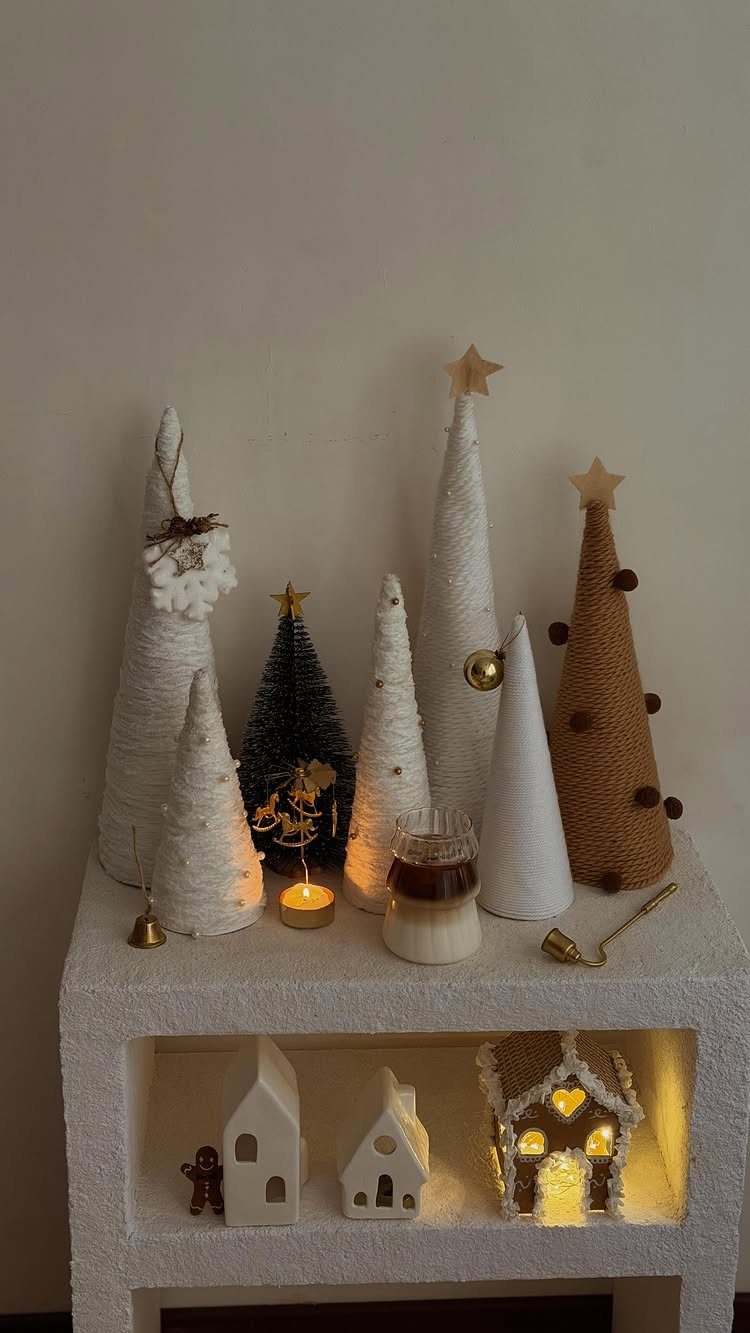 Yarn wrapped tabletop Christmas trees in white and brown on a white shelf.