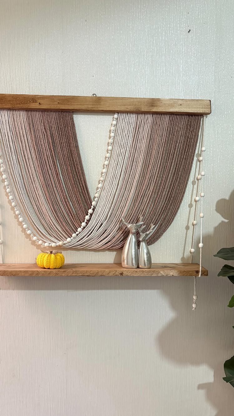 Yarn wall hanging with wood beads, silver deer figurines, and a yellow pumpkin.